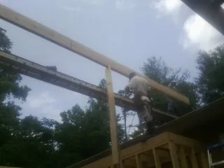 Carpenter setting a ridge beam over a new addition frame — Ice Dam Removal by Roofing Brothers in Baxter